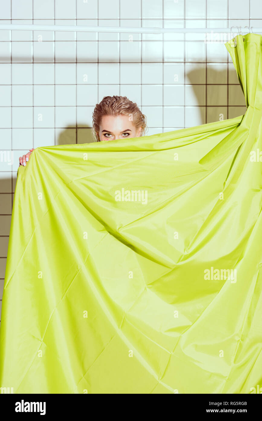 Junge Frau versteckt sich hinter grünen Vorhang mit Kopie Raum in der Dusche Stockfoto