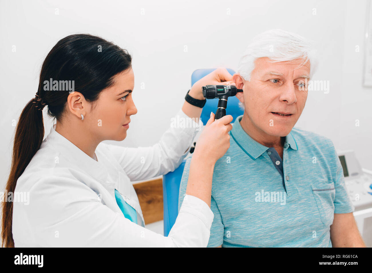Arzt untersucht ältere Patienten Ohr, mit Otoskop, in der Arztpraxis. Ältere Menschen erhalten medizinische Ohr Untersuchung an der Klinik. Stockfoto