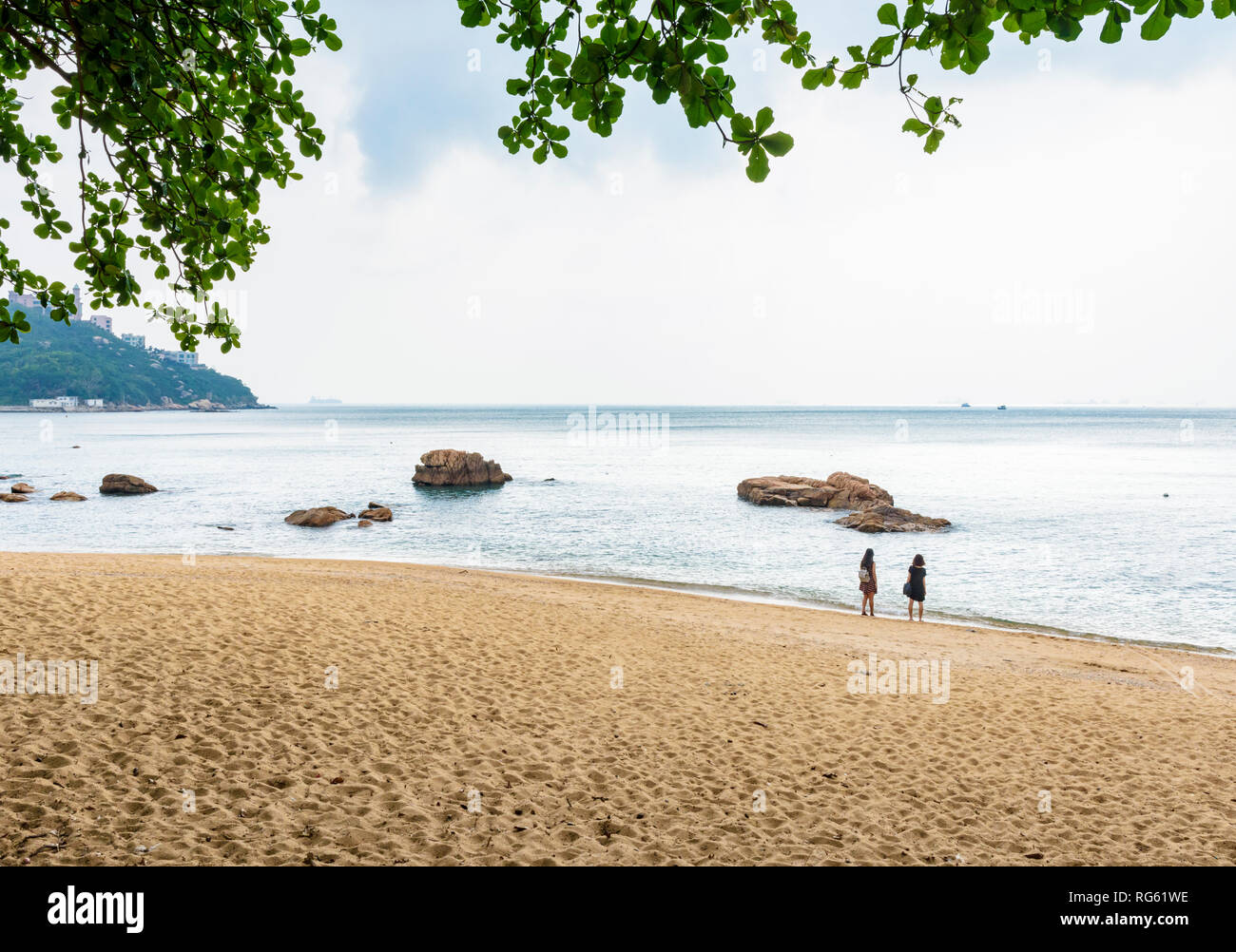 Zwei Frauen schauen Sie sich die Aussicht auf das Meer am kleinen Strand neben Stanley, Hong Kong Stockfoto