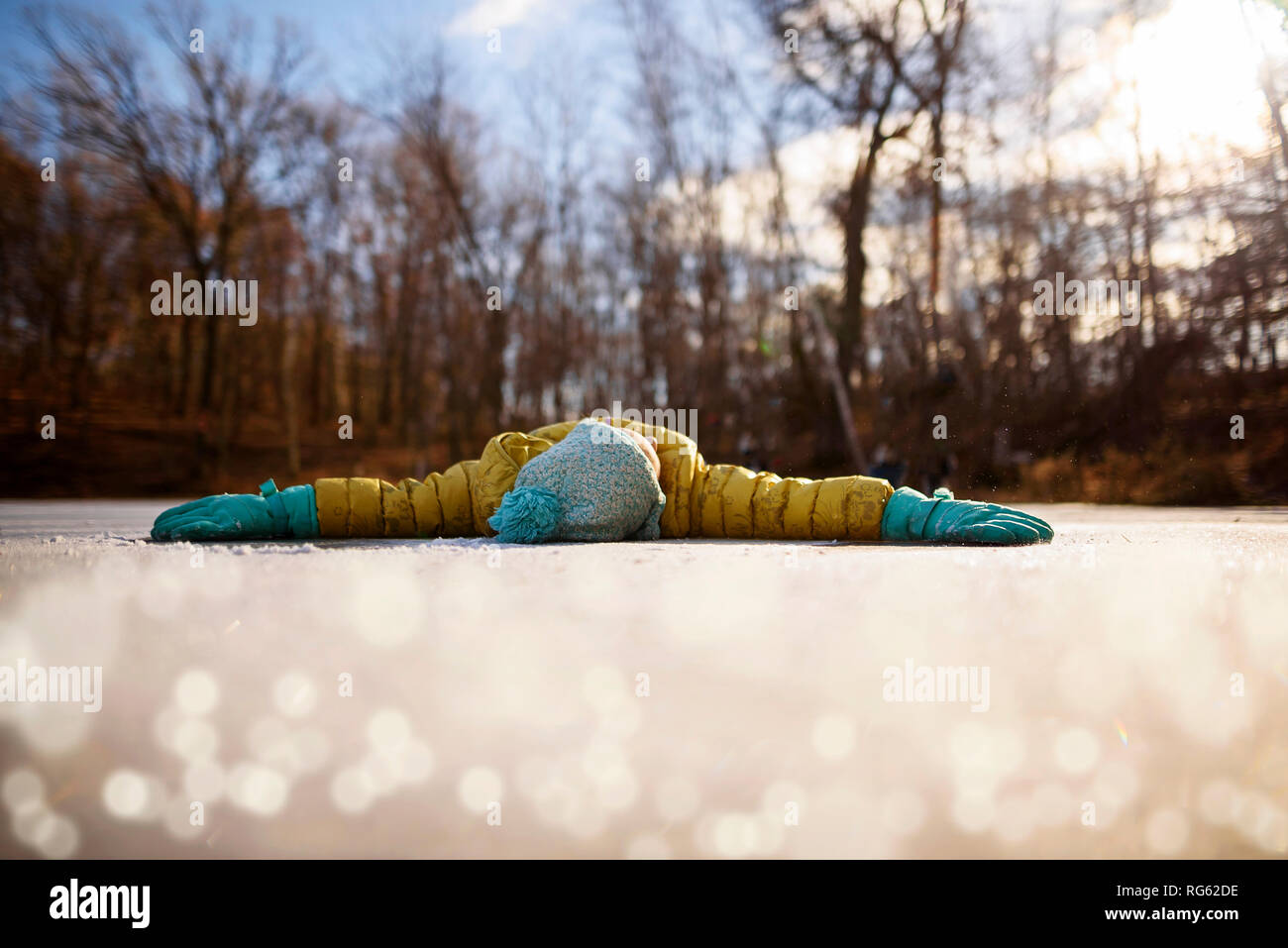 Mädchen auf einem zugefrorenen Teich mit ihren Armen liegend ausgestreckt, United States Stockfoto