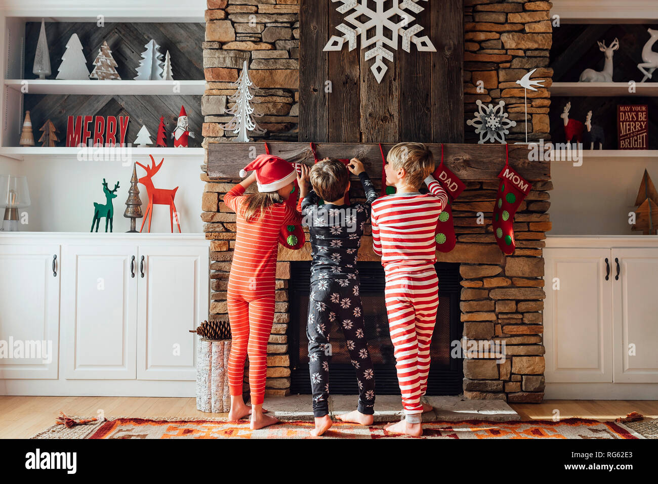Drei Kinder hängen Weihnachten Strümpfe auf einem Kamin Stockfoto