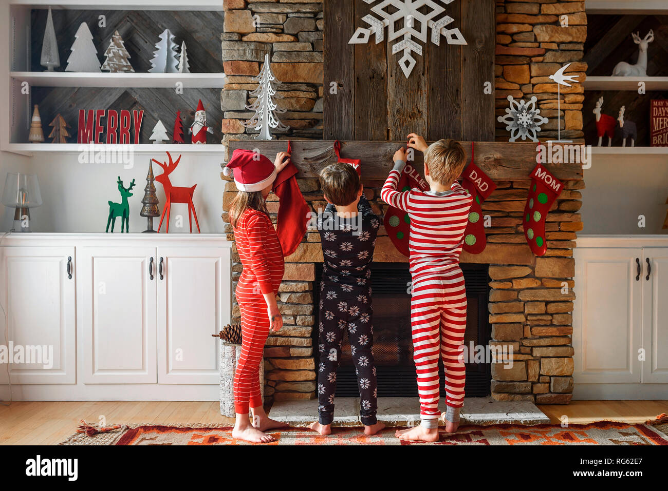 Drei Kinder hängen bis Weihnachten Strümpfe auf einem Kamin Stockfoto