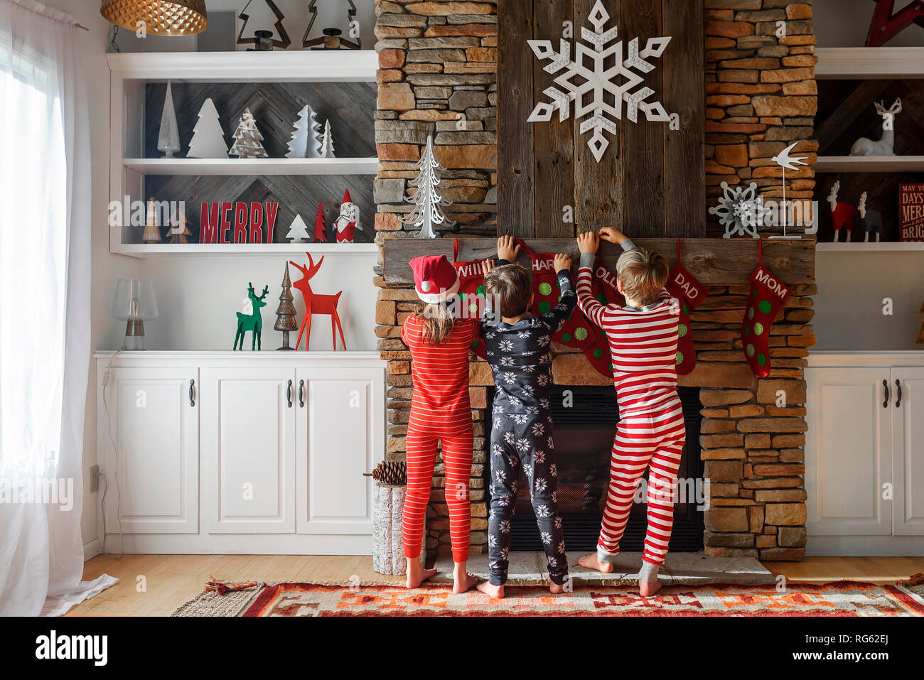 Drei Kinder hängen bis Weihnachten Strümpfe auf einem Kamin Stockfoto