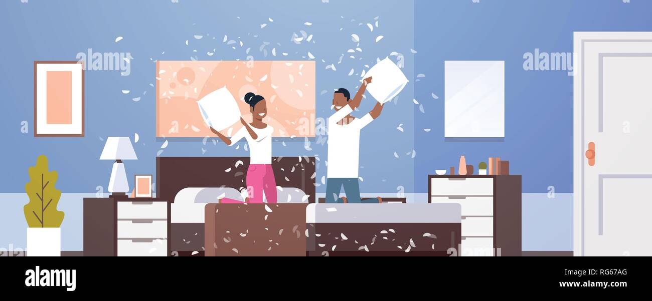 Junges Paar mit Kissen Schlacht afrikanische amerikanische Mann Frau genießen die Zeit zusammen Liebhaber Beat mit Kopfkissen auf dem Bett zu Hause modernes Apartment Schlafzimmer Stock Vektor
