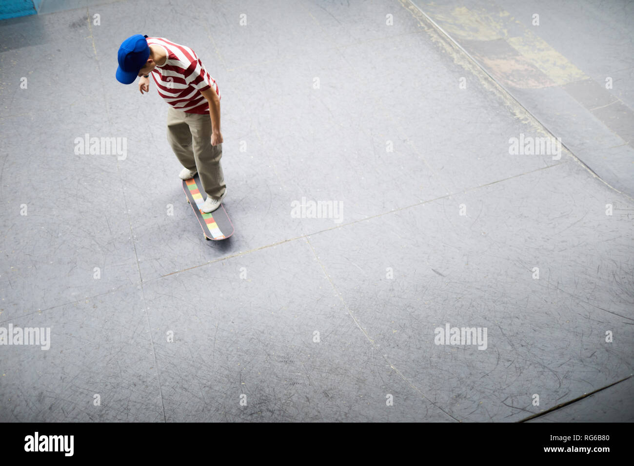 Der junge Mann in der casualwear auf Skateboard und entlang besonders flachen Bereich für acrtivities Stockfoto