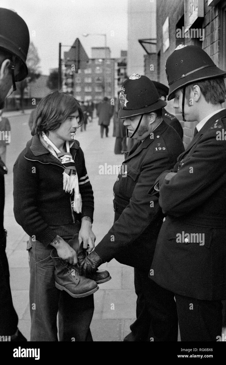 Fußballfans der 1970er Jahre UK. Manchester City Fußballfan verhinderte den Eintritt in den QPR-Fußballplatz der Queens Park Rangers, weil er Arbeitsschuhe mit Metallkappe trägt. Die Polizei sagte, er müsse sie ausziehen und durfte dann ins Fußballstadion. Das Football-Spiel der Polizei am Samstag. 1972 UK HOMER SYKES Stockfoto