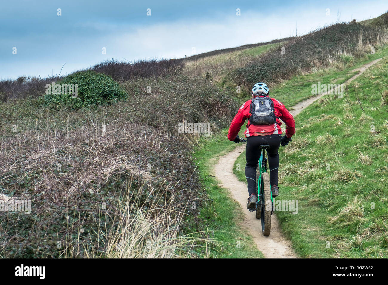 Ein Mountainbiker Radeln entlang ein Fußweg an der Küste von Cornwall. Stockfoto