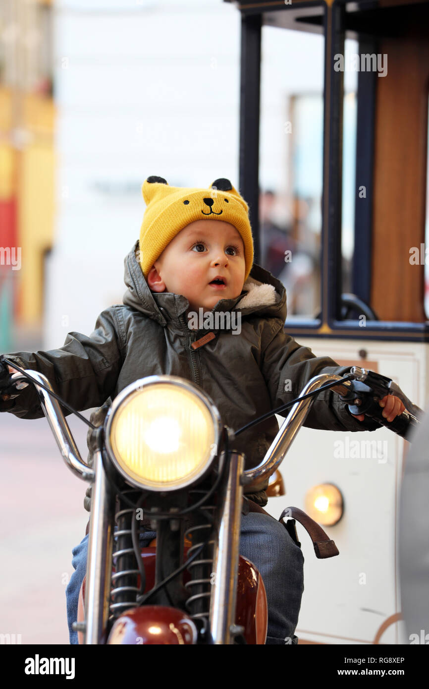 Cute Baby Junge sitzt auf einem Oldtimer Motorrad, der kleine Junge ist  Lachen auf dem Karussell, Nahaufnahme, Porträt Stockfotografie - Alamy