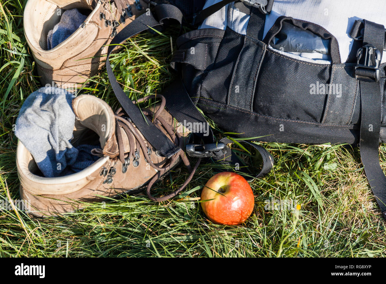 Bergschuhe, Rucksack und Apple auf einer Wiese Stockfoto