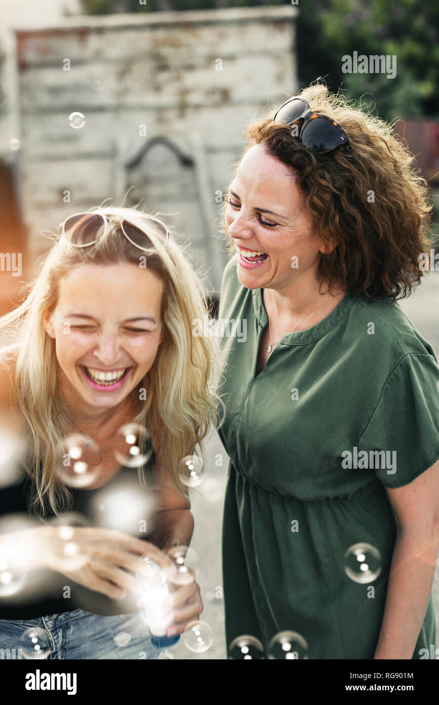 Zwei glückliche Frauen mit Seifenblasen im Freien Stockfoto