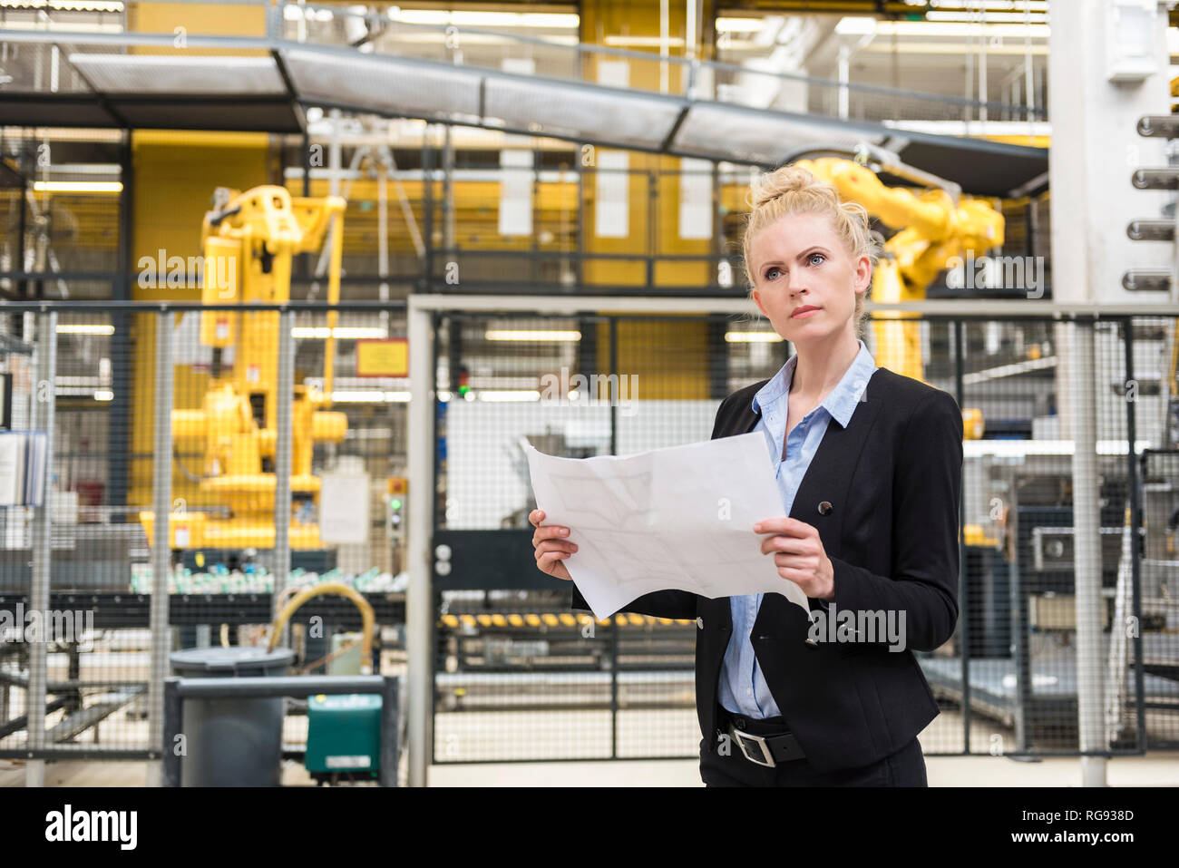 Frau mit Plan in der Factory Shop Floor mit Industrieroboter Stockfoto