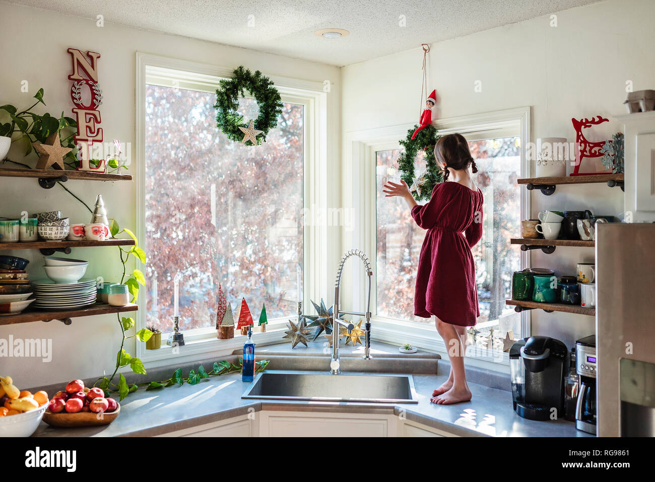 Mädchen stehen auf einer Küchenarbeitsplatte herauf Weihnachtsdekorationen Stockfoto