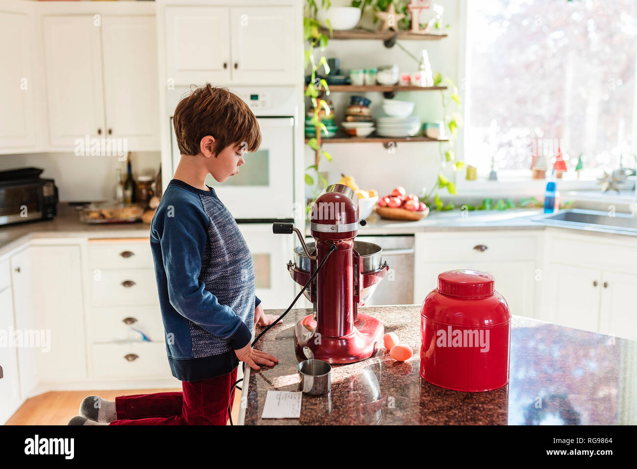 Junge kniend auf Hocker in der Küche einen Kuchen Stockfoto