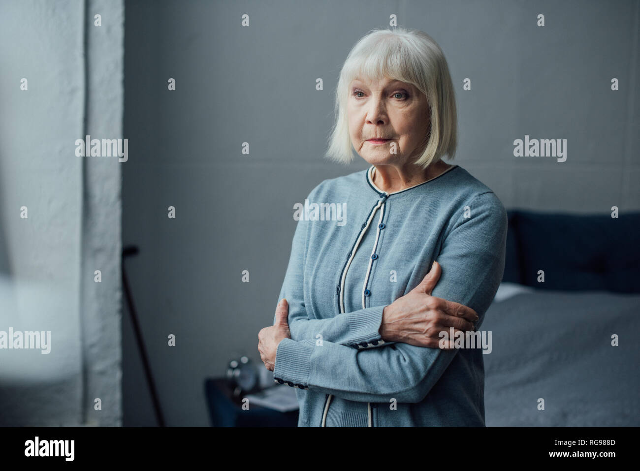 Nachdenklich ältere Frau in lässigen Pullover mit Waffen zu Hause gekreuzt Stockfoto