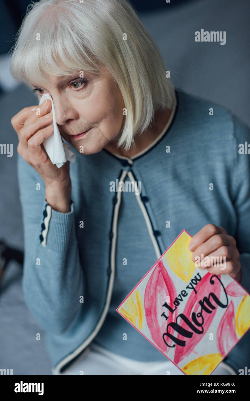 Ältere Frau mit Karte mit 'Ich liebe dich Mama"-Schriftzug, Schreien und wischte sich mit dem Taschentuch zu Hause Stockfoto