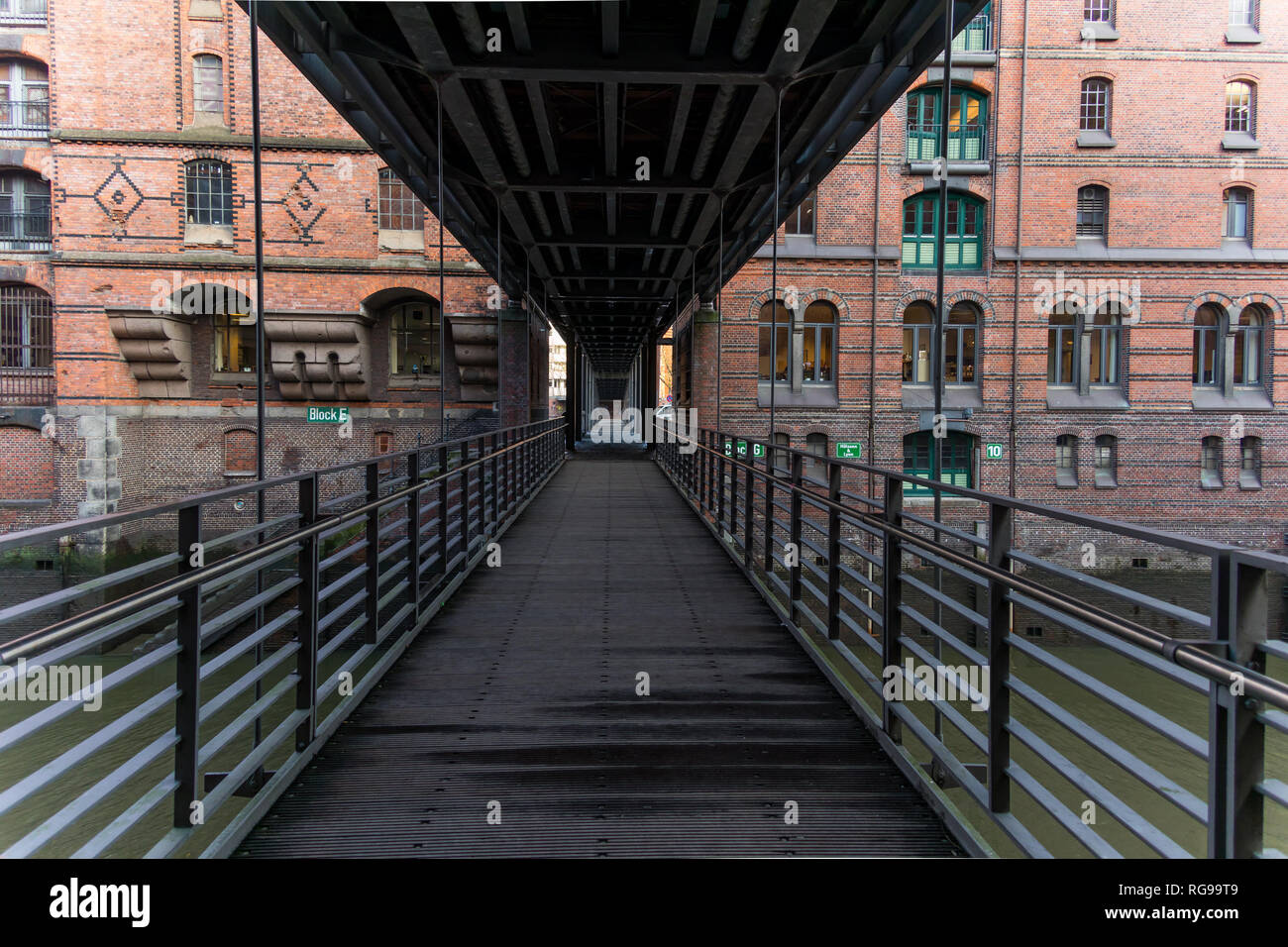 Eine Fußgängerbrücke verbindet zwei Reihen von modernisierten Lagern in der Speicherstadt, Hamburg, im alten Hafengebiet. Stockfoto