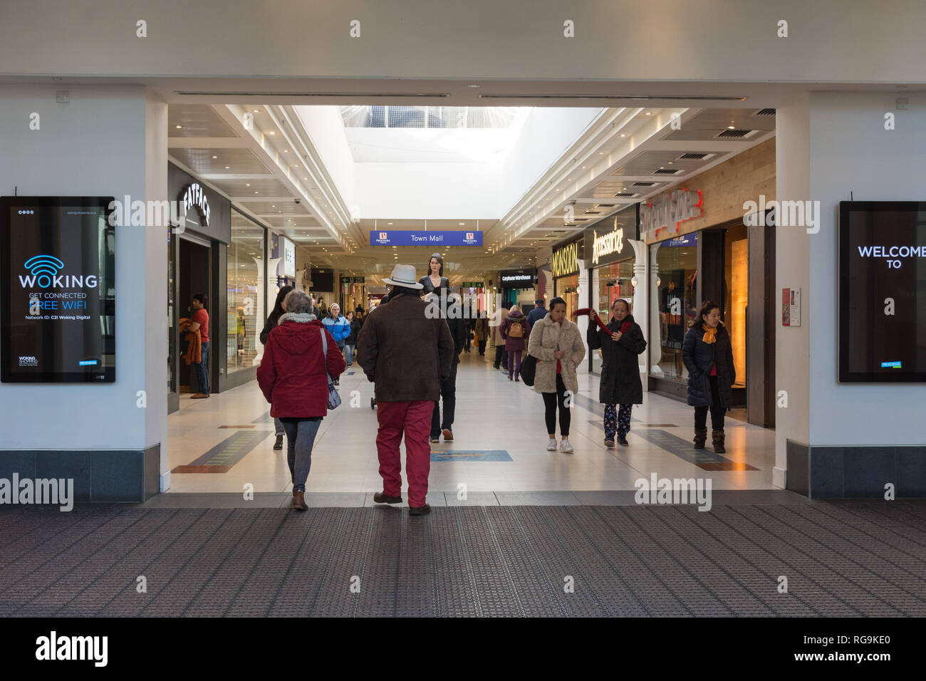 Menschen (Shopper) gehen in die und aus der Pfauen Shopping Center, ein Einkaufszentrum in Woking, Surrey, Großbritannien Stockfoto