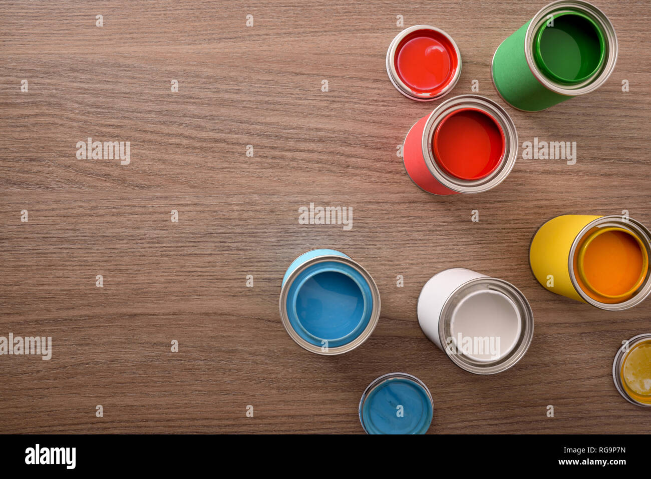 Fünf offene Farbdosen und ihre Abdeckungen auf hölzernen Tisch. Ansicht von oben. Horizontale Komposition. Stockfoto