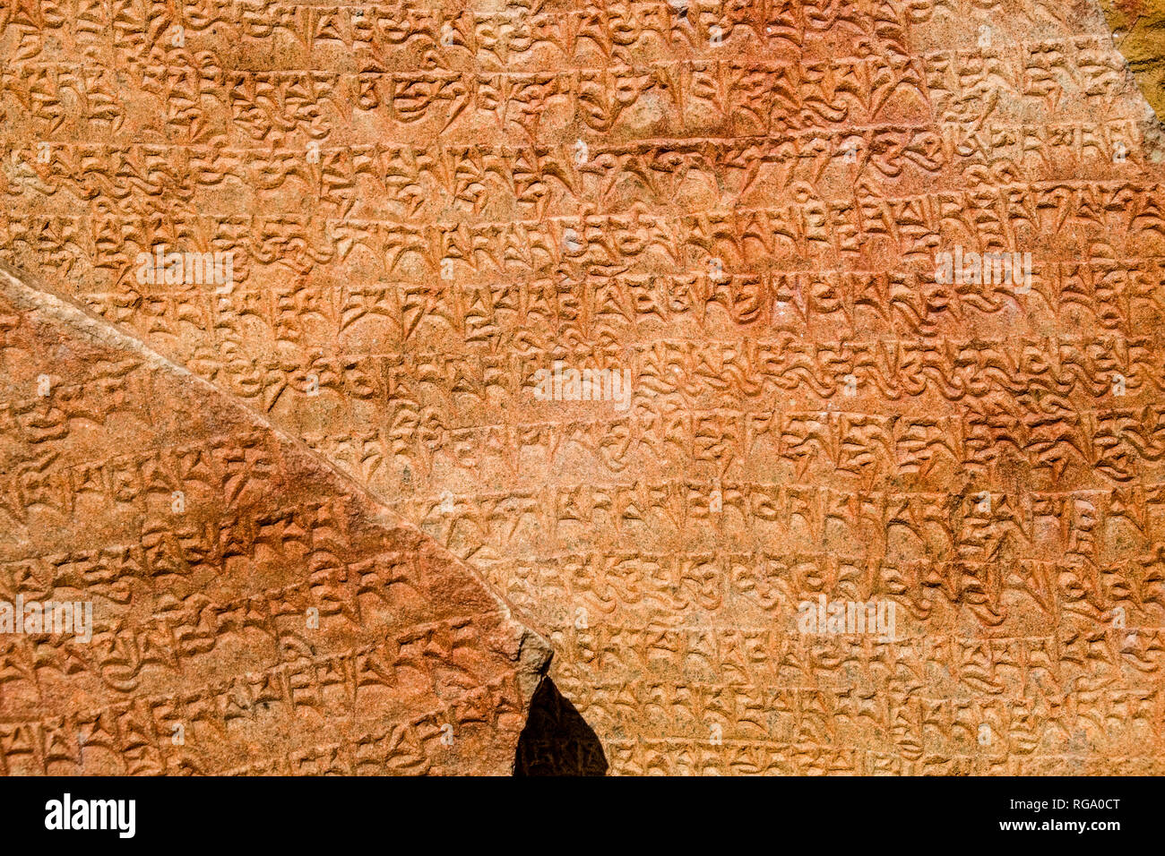 Orangefarbene Mani Stein mit dem Rock buddhistische Mantra von Avalokiteshwara, die Om Mani Padme Hum geschnitzt Stockfoto