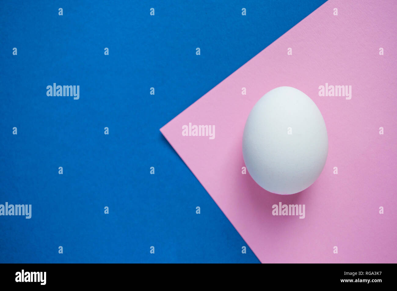 Eine weiße einziges Ei auf dunklem Blau und Pastell rosa Hintergrund mit Copyspace. Stockfoto