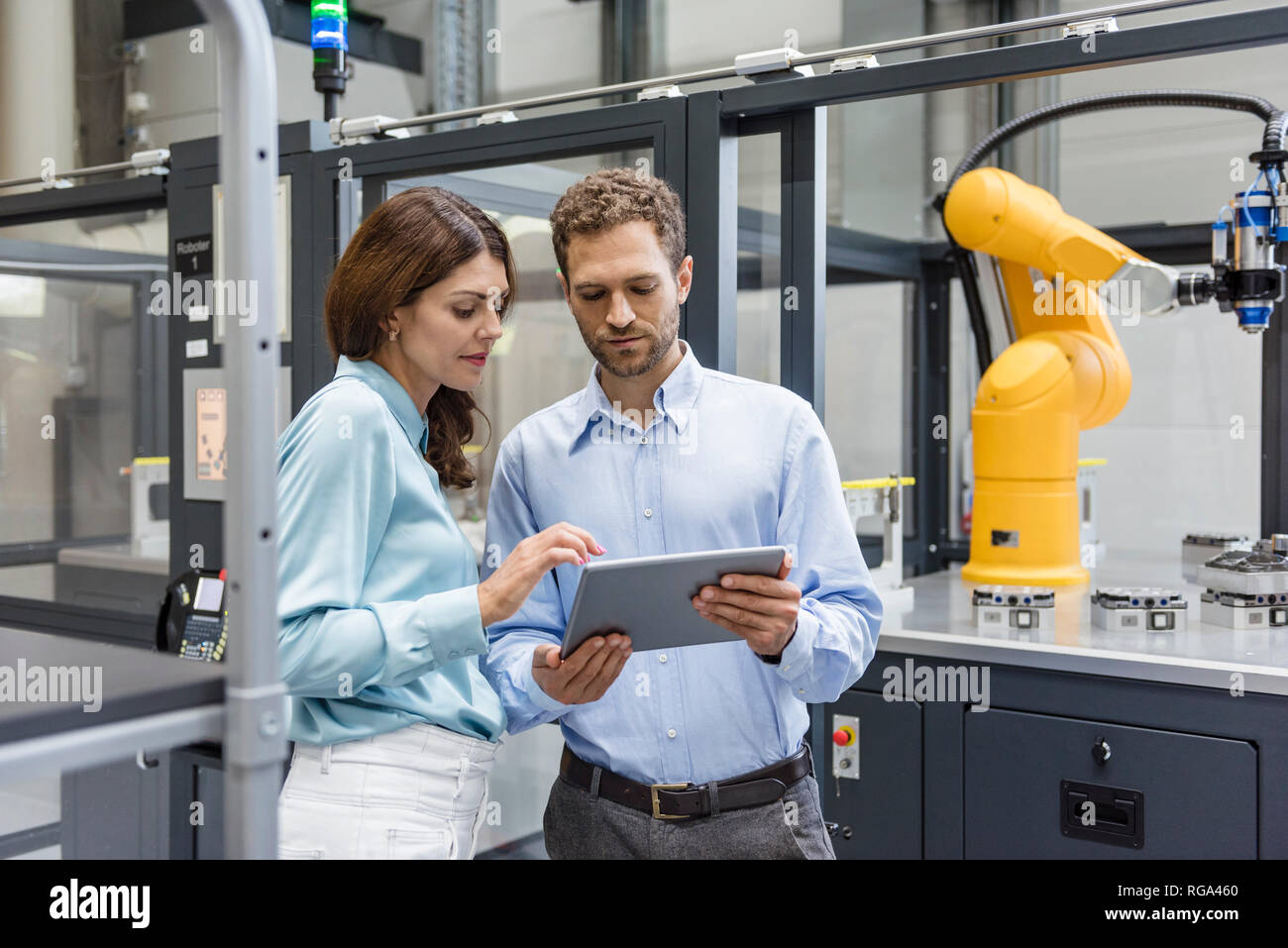 Kollegen in High-Tech Unternehmen controlling Industrieroboter, mit digitalen Tablet Stockfoto