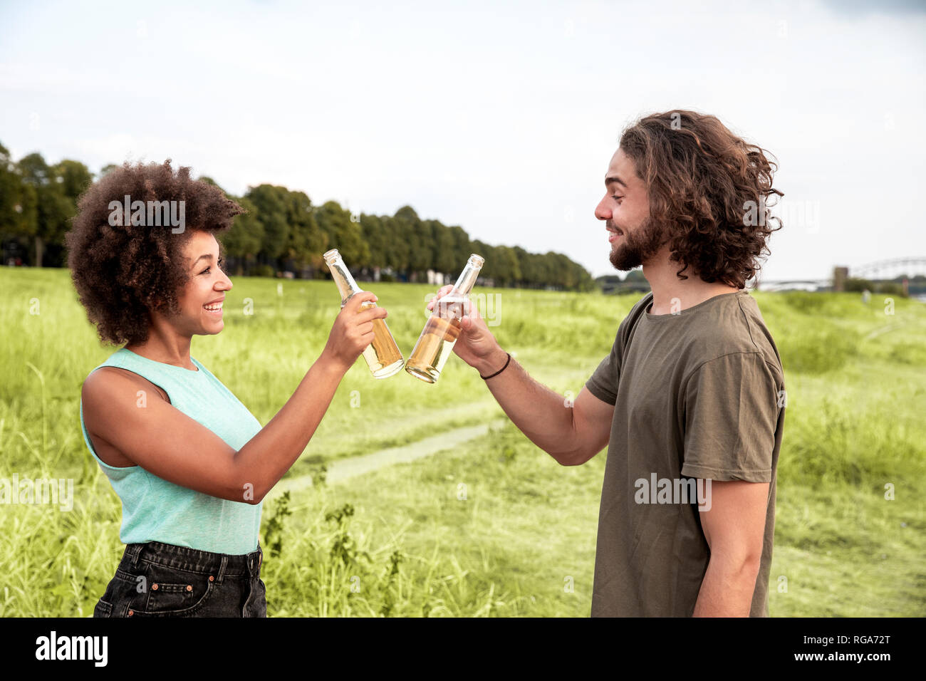 Glückliches Paar klirren Bierflaschen in die Natur Stockfoto