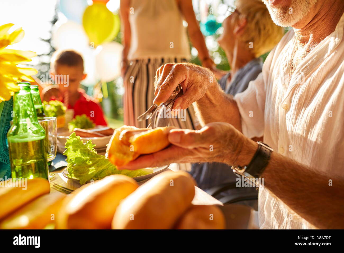 Ältere Menschen Vorbereiten einer heißen Hund auf einer Gartenparty Stockfoto