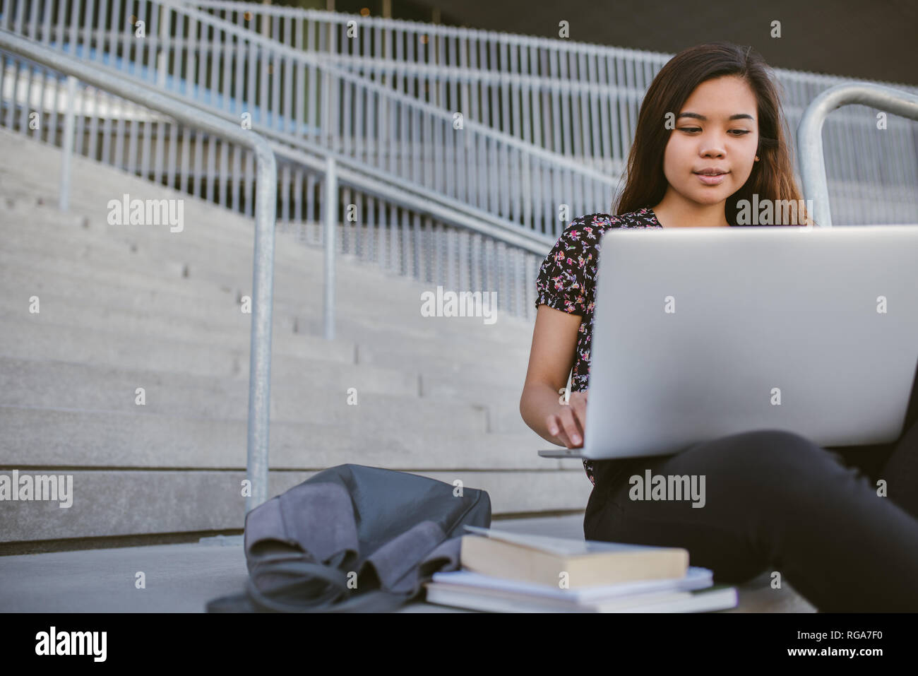 Junge asiatische Studentin mit einem Laptop auf dem Campus Stockfoto