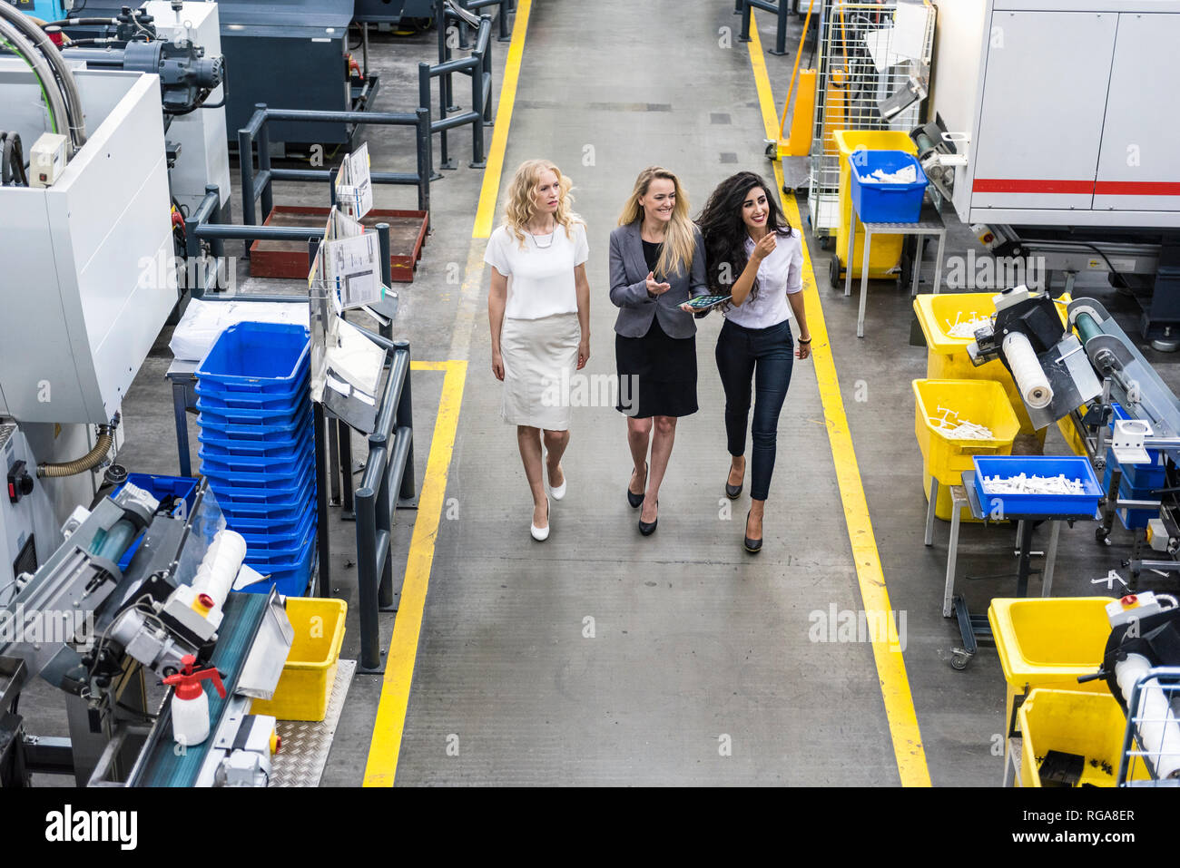 Drei lächelnde Frauen mit Tablet wandern in Factory Shop Boden Stockfoto