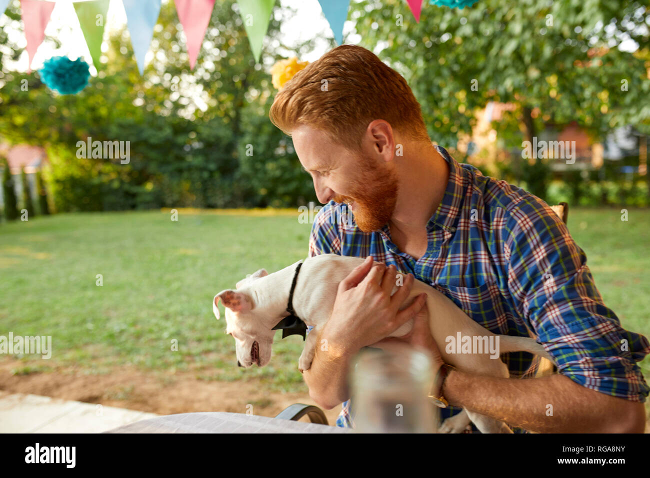 Glücklicher Mann mit Hund auf einer Gartenparty Stockfoto