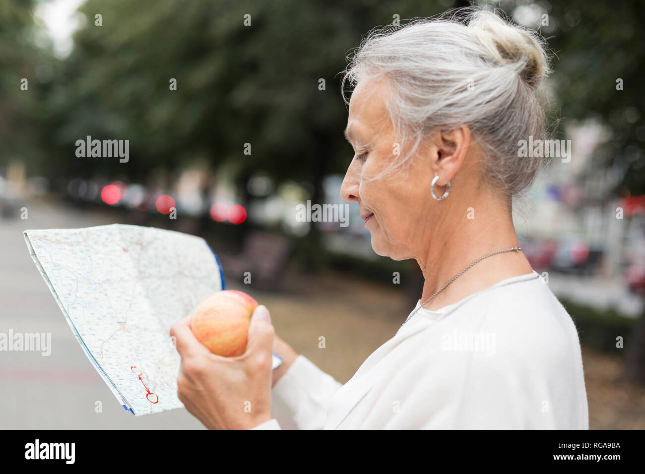 Ältere Frau im Freien holding Karte und Apple Stockfoto