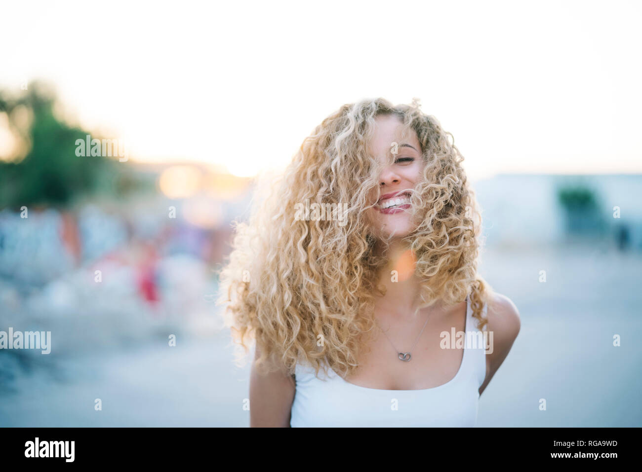 Porträt der glückliche junge Frau mit blonden Korkenzieherlocken Stockfoto