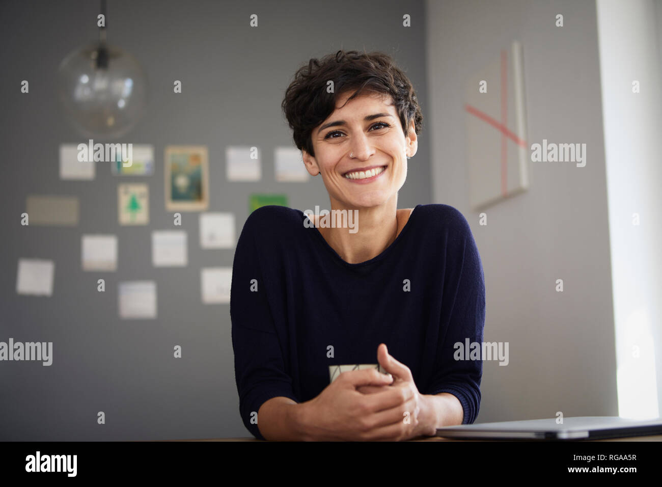 Porträt der lächelnde Frau am Tisch zu Hause sitzen Stockfoto