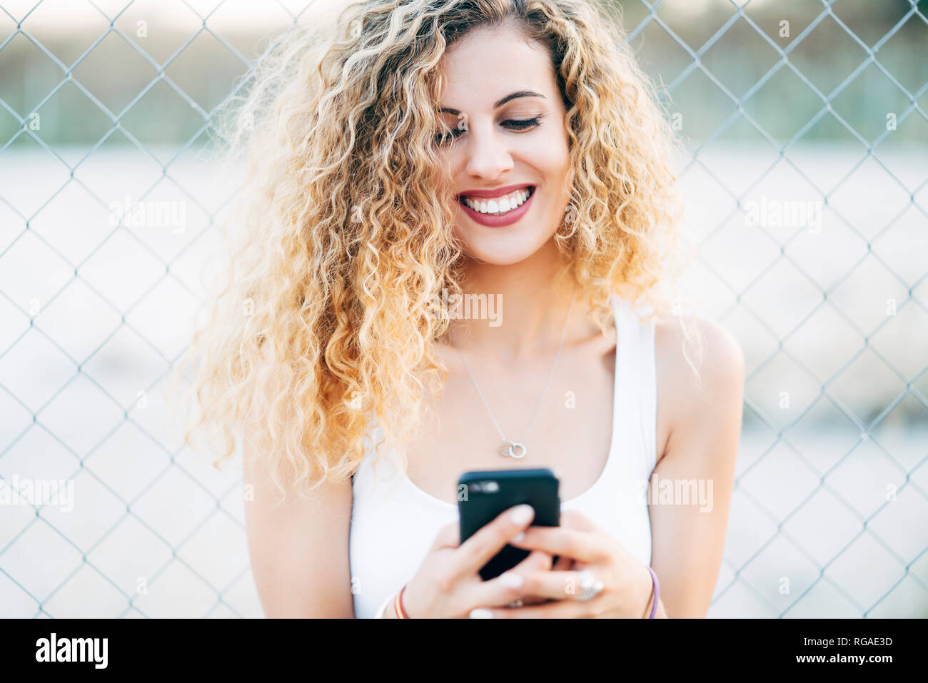 Portrait von Lachen blonde junge Frau am Handy suchen Stockfoto