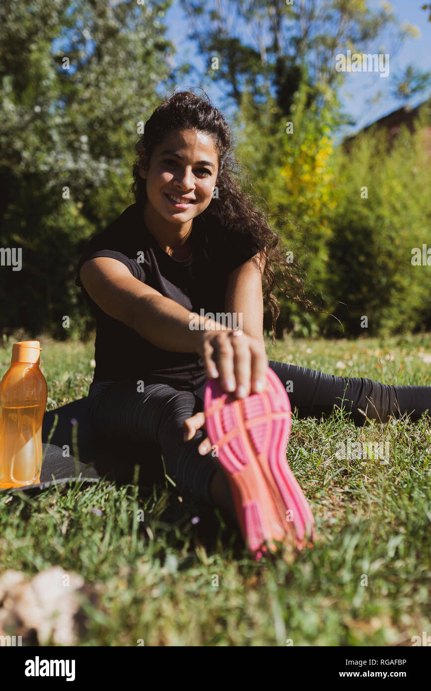 Sportliche junge Frau ihr Bein strecken auf einer Wiese Stockfoto