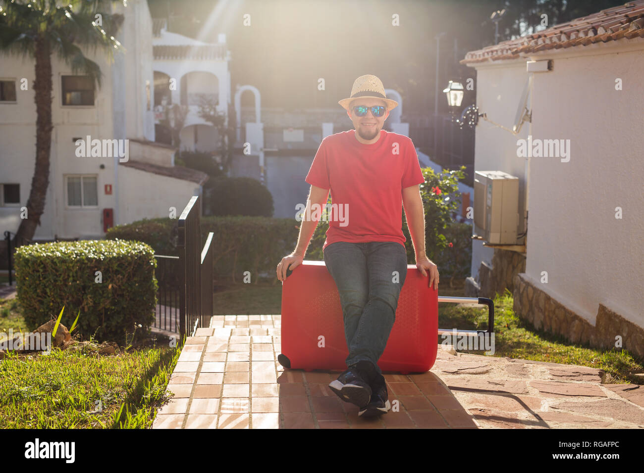Urlaub, Reisen und Ferien Konzept - stattlicher Mann mit roten Koffer am Hotel angekommen Stockfoto