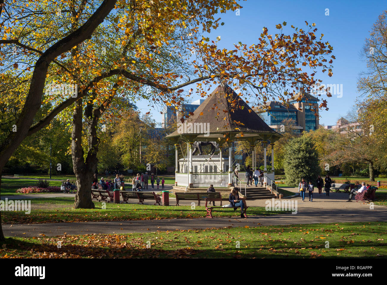 Die Menschen genießen einige späte Herbst Sonnenschein am Musikpavillon in Forbury-gärten, Reading, Berkshire Stockfoto