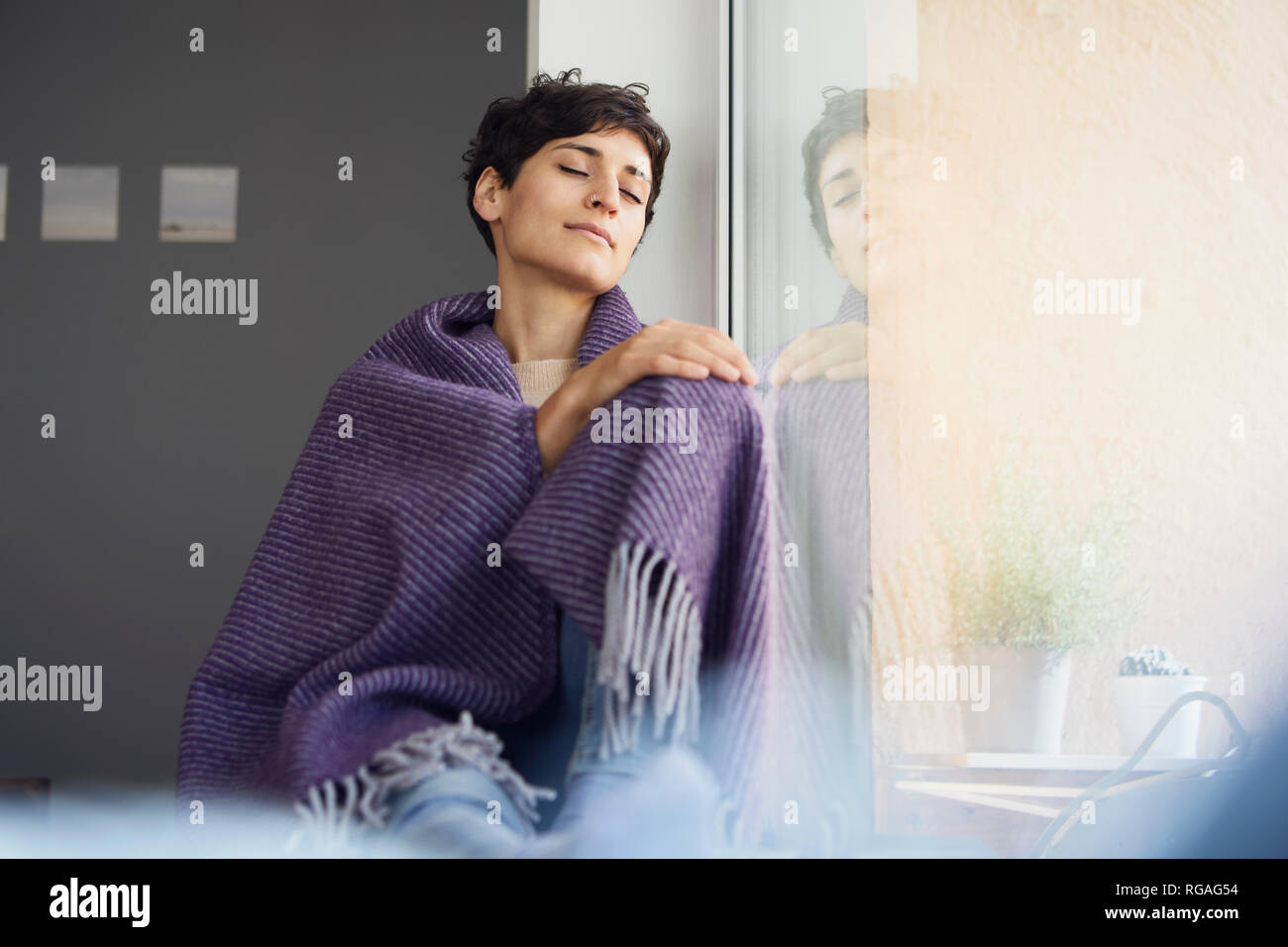 Entspannt Frau zu Hause sitzt am Fenster Stockfoto
