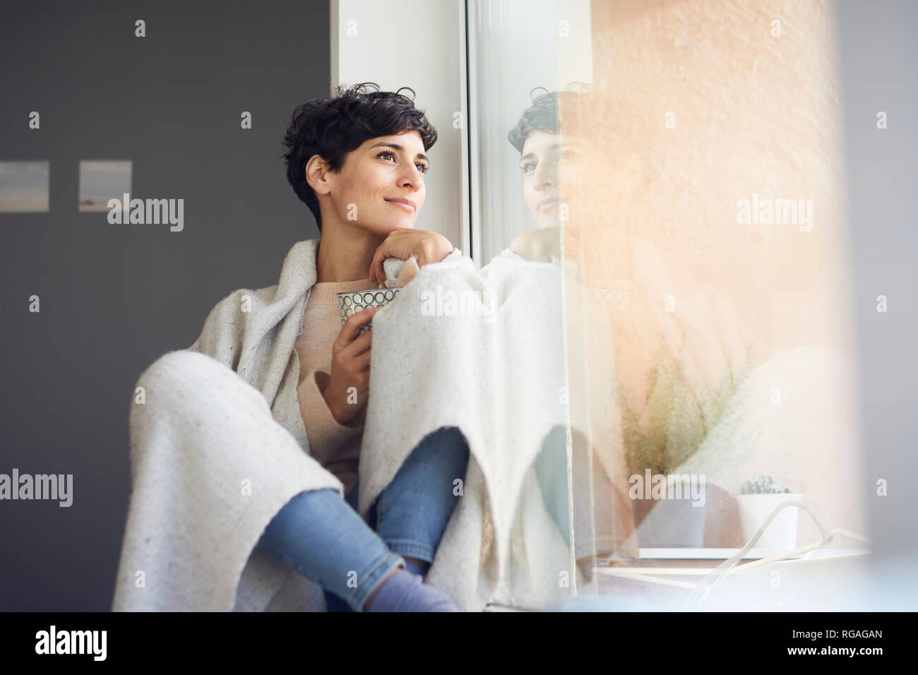 Entspannt Frau zu Hause sitzt am Fenster Stockfoto