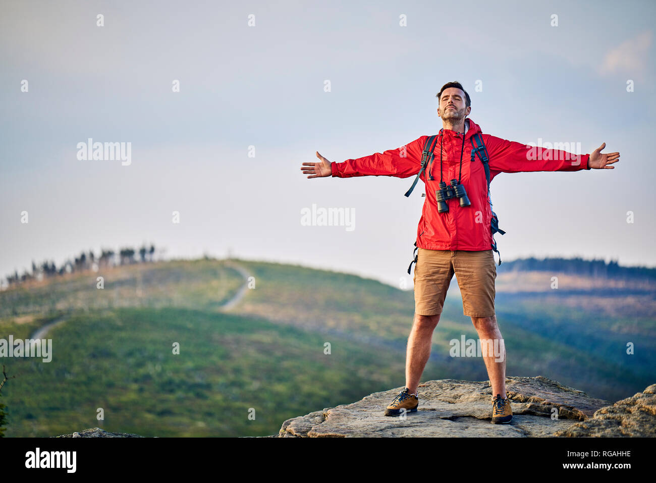 Mann stand mit ausgebreiteten Armen auf dem Berg oben Stockfoto