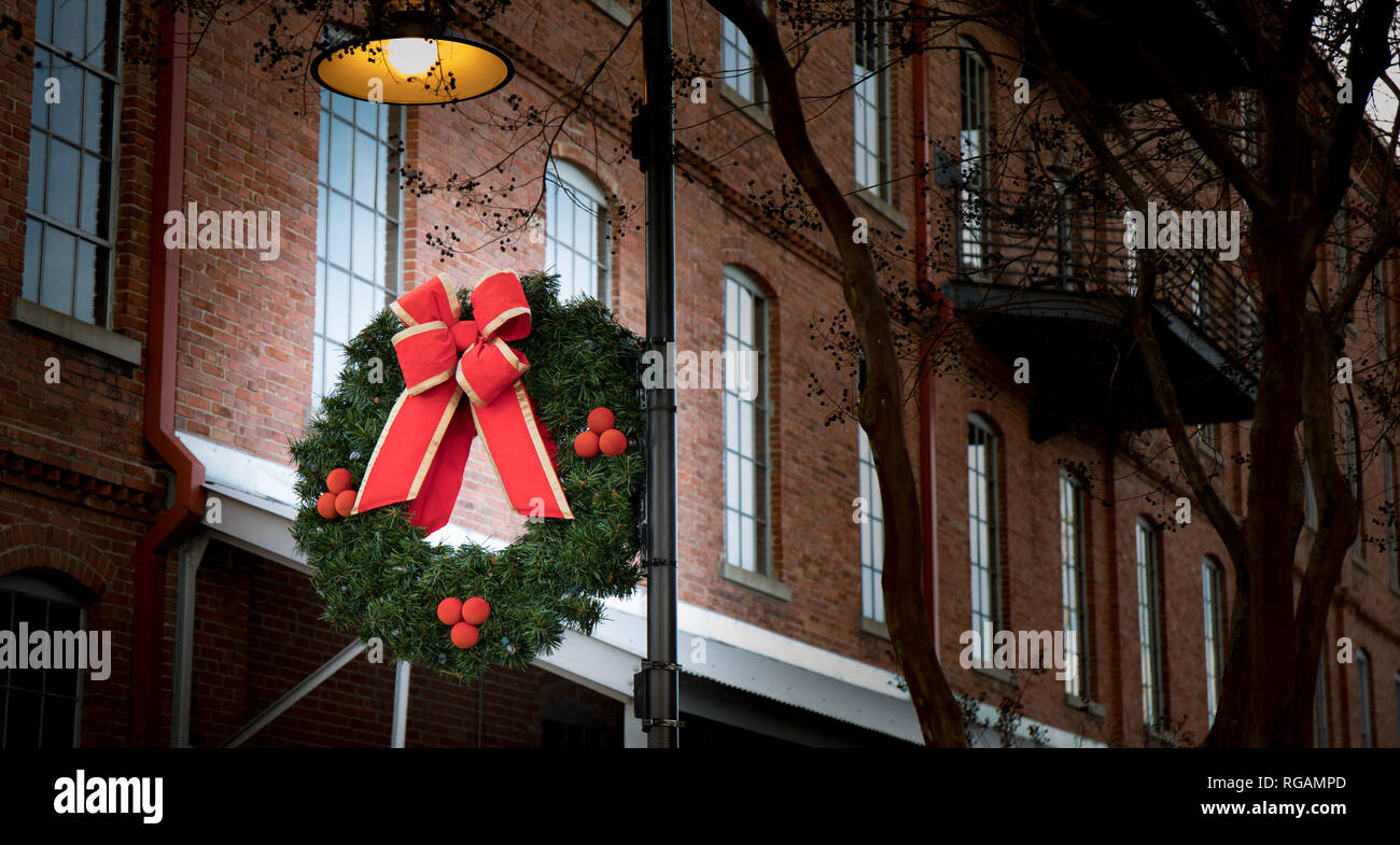 A Christmas wreath Dekoration hängen an einer Laterne im urbanen Raum. Stockfoto