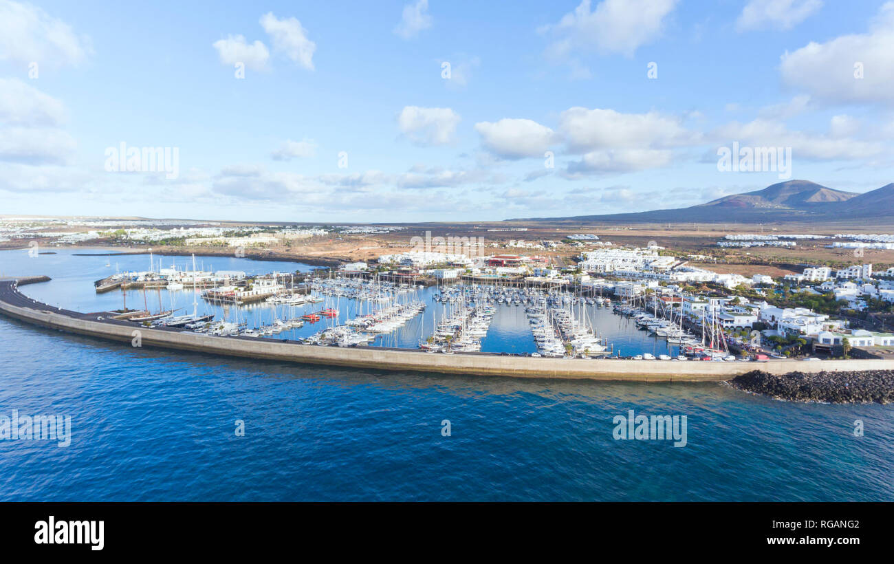 Luftaufnahme von Playa Blanca Rubicon Marina, mit Segelbooten, Yachtcharter, Urlaub Wohnungen, vulkanische Berge im Hintergrund in Lanzarote, Kanarische Inseln Stockfoto