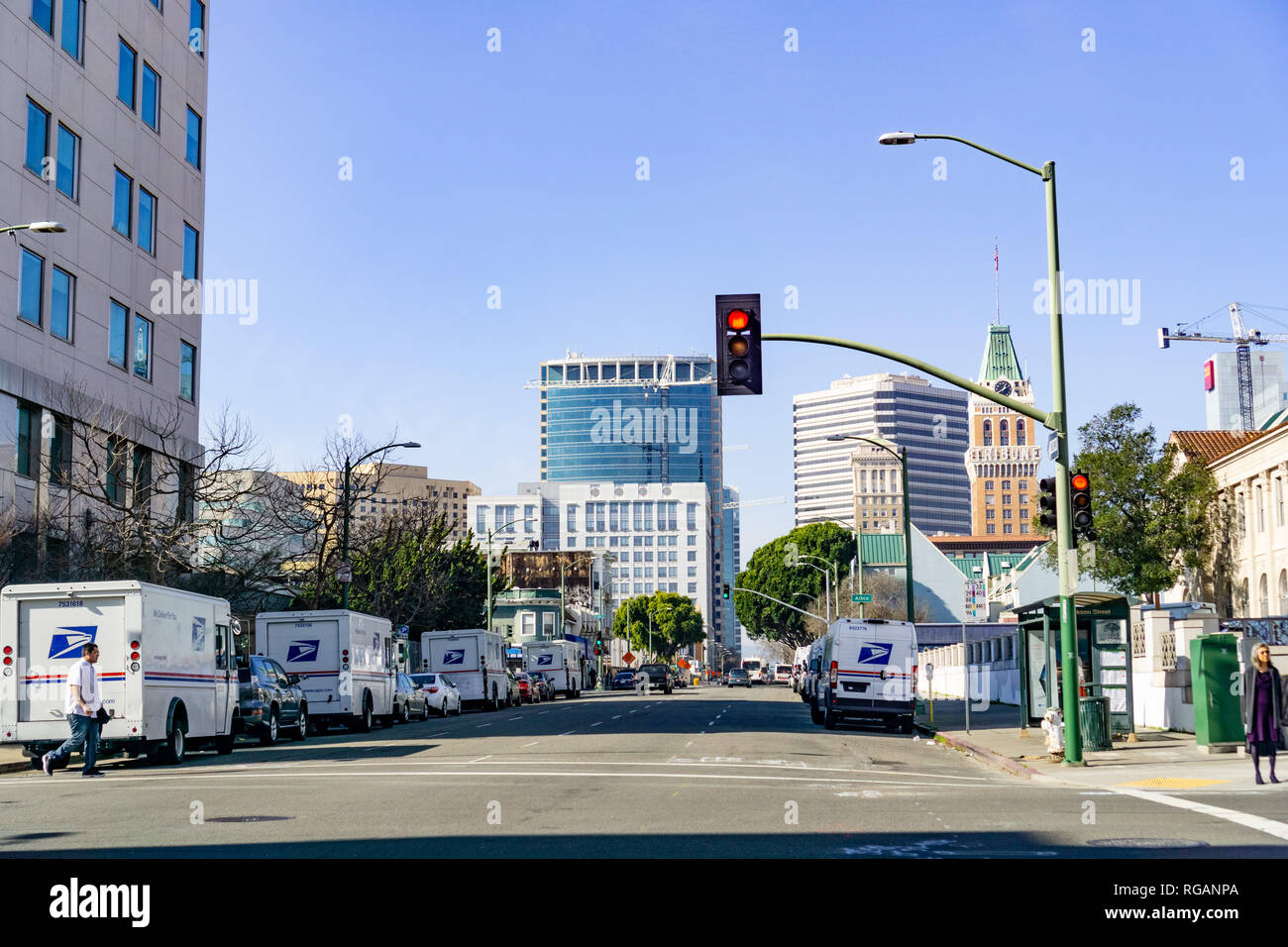 Januar 27, 2019 Oakland/CA/USA - Landschaft in der Innenstadt von Oakland, San Francisco Bay Area; USPS Fahrzeuge auf beiden Seiten der Straße geparkt Stockfoto
