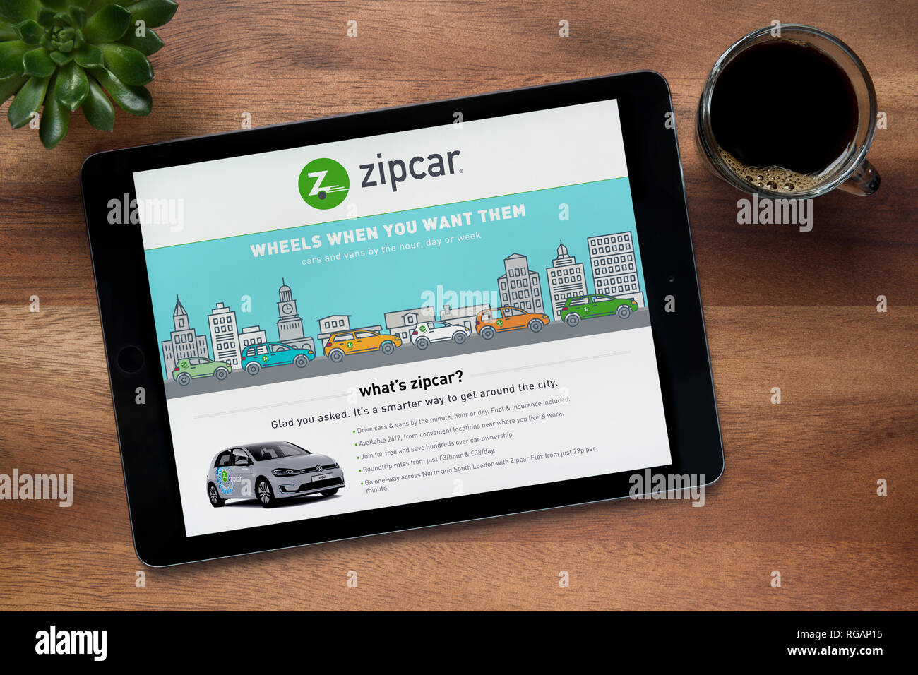 Die Website von zipcar ist auf einem iPad Tablet gesehen, auf einer hölzernen Tisch zusammen mit einem Espresso und einem Haus Anlage (nur redaktionelle Nutzung). Stockfoto