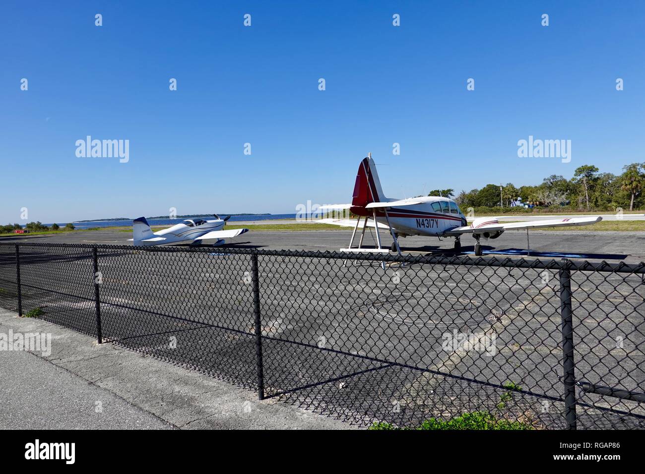Piper PA 23 160 Apache beschädigte Flugzeug und kleine, einmotorige Wasserflugzeug am Ende der Insel Landebahn geparkt, Cedar Key, FL, USA. Stockfoto