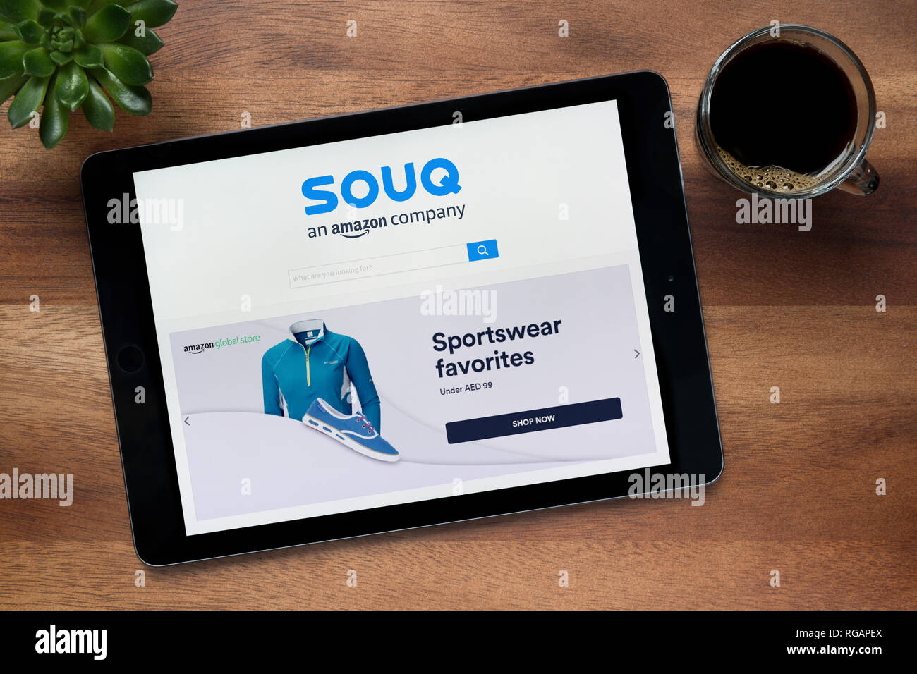 Die Website von Souq.com ist auf einem iPad Tablet gesehen, auf einer hölzernen Tisch zusammen mit einem Espresso und einem Haus Anlage (nur redaktionelle Nutzung). Stockfoto