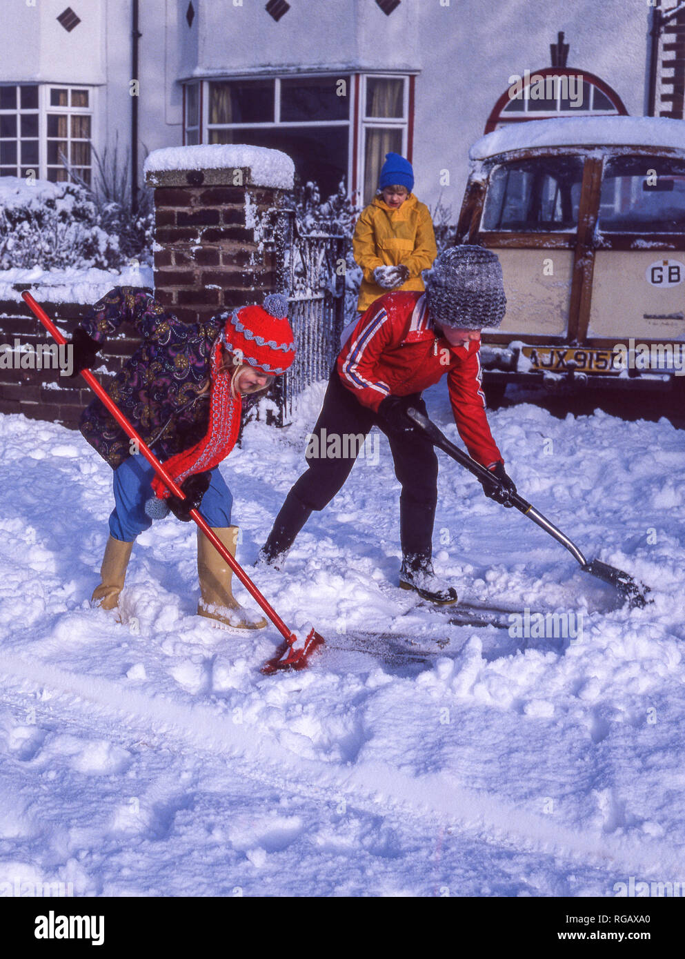 Zwei junge Kinder, die versuchen, tiefen Schnee von einer Straße Bürgersteig zu löschen. Stockfoto
