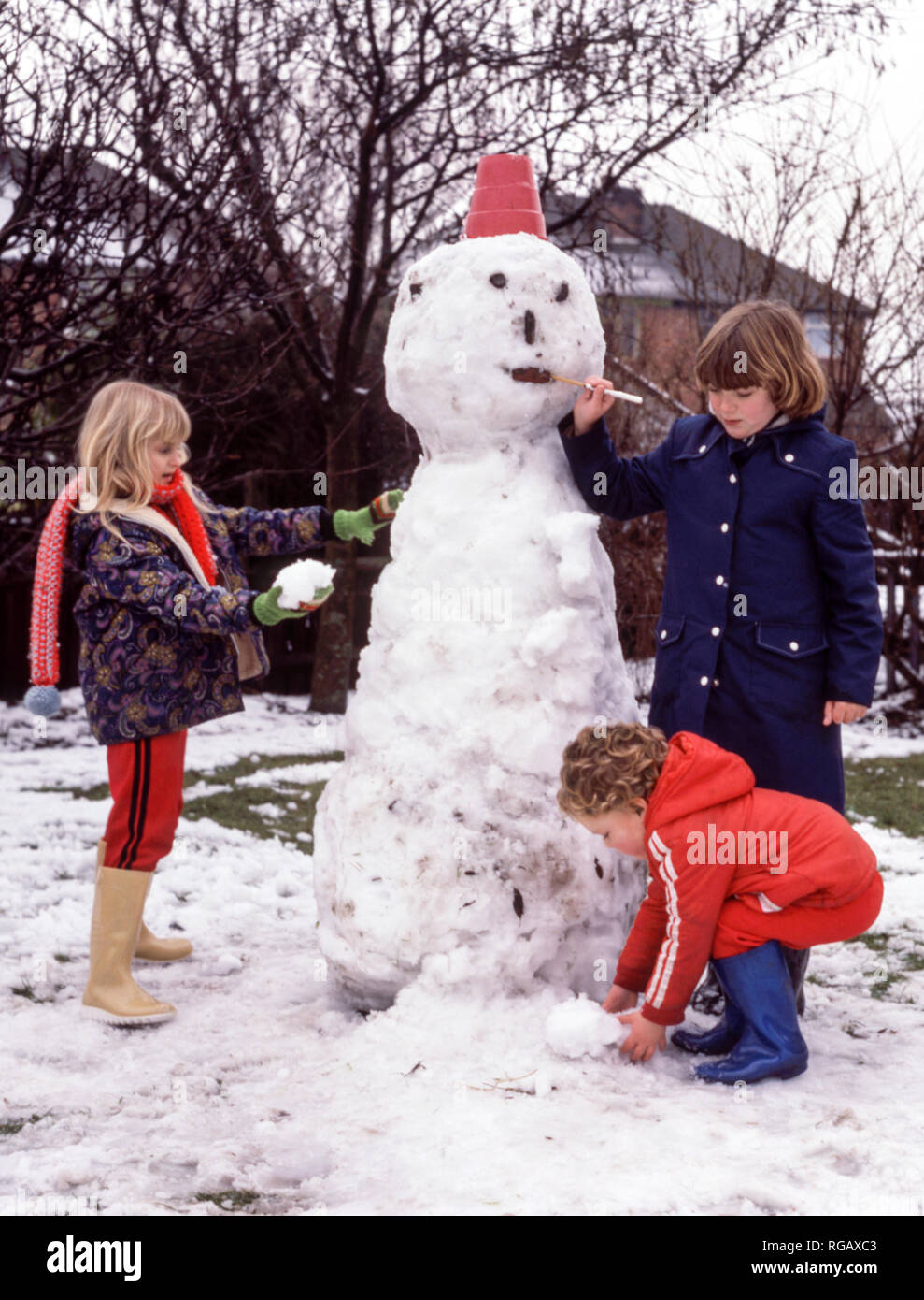 Drei Kinder einen Schneemann im Garten. Stockfoto