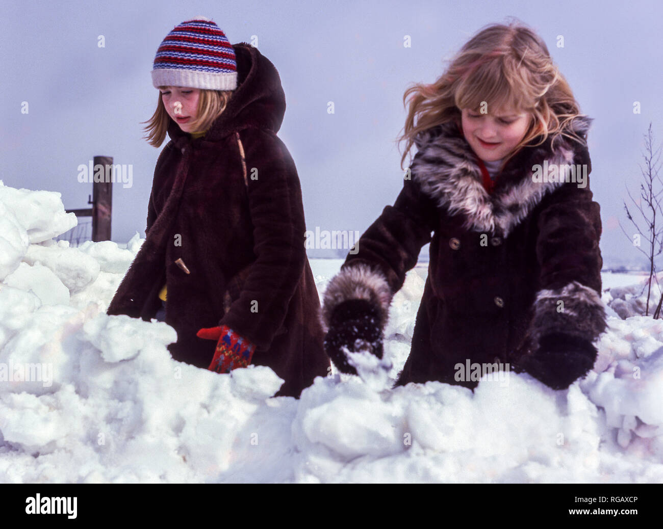 Zwei junge Mädchen, in tiefem Schnee, die versuchen, ein Iglu zu machen. Stockfoto
