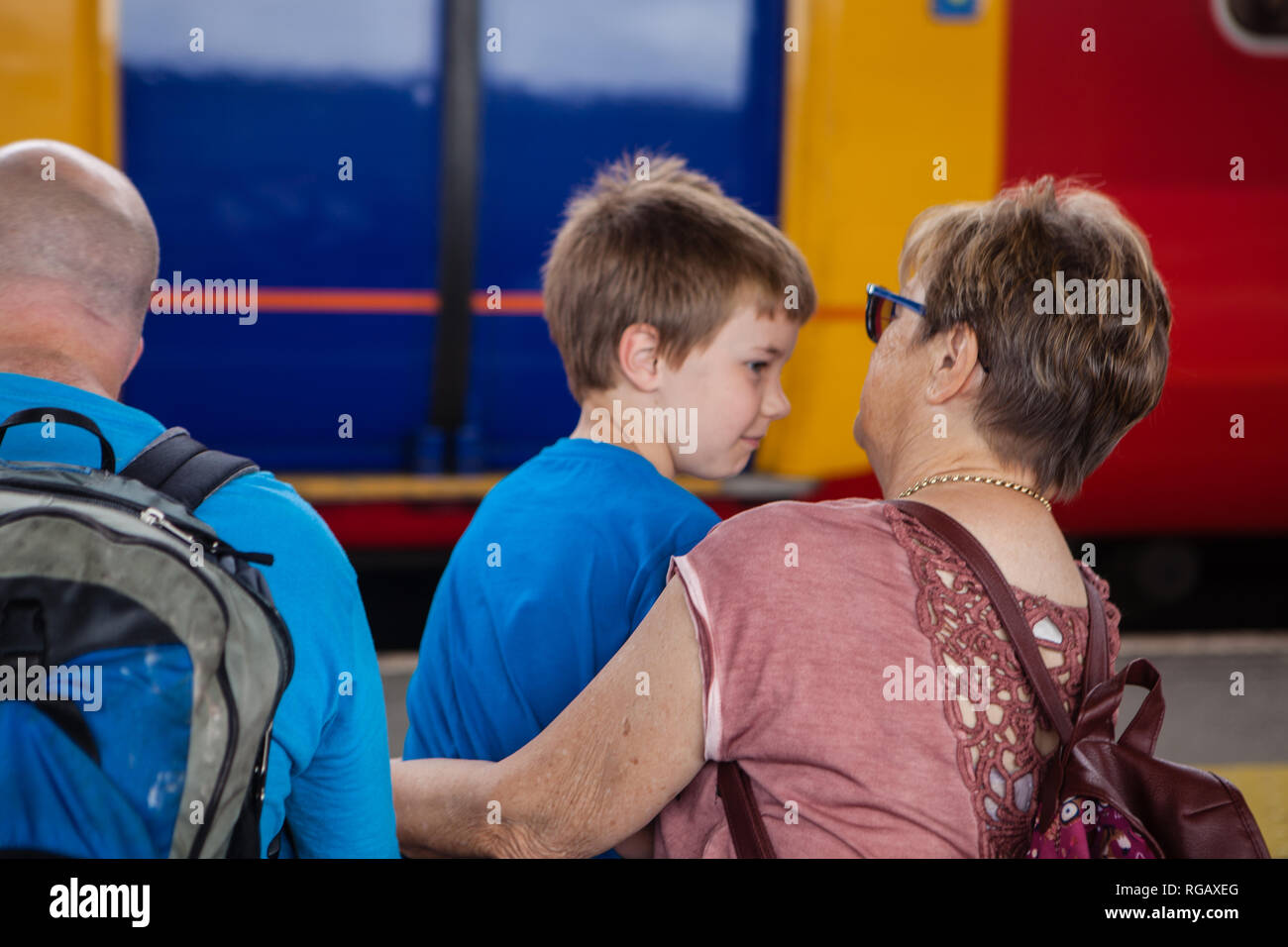 Latina Familie sitzt auf einem Bahnsteig mit dem Zug im Hintergrund wartet, um zu reisen. Stockfoto